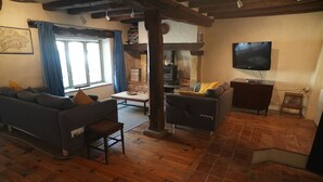 A living room with a sofa, armchair, wooden floor, TV, and a fireplace. - Charming 3 Bed/2 Bath House in Medieval Village (Tillac)