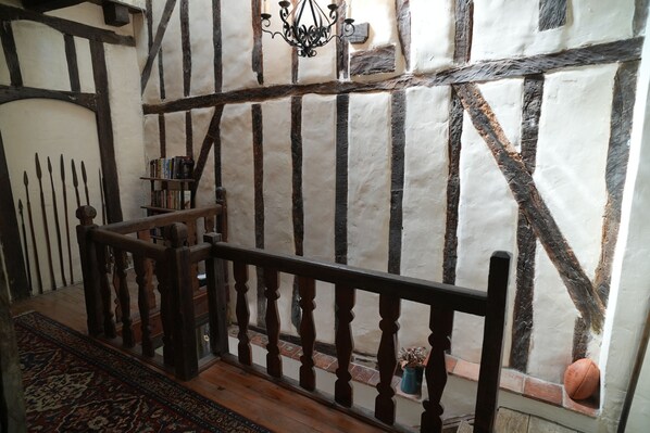 Une pièce avec une charpente en bois apparent, un escalier en bois, un lustre et un petit ballon de basket.
