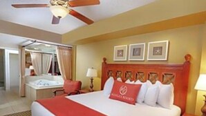 Ein Hotelzimmer mit einem großen Bett, einem Deckenventilator, einem Nachttisch und einem Schreibtisch mit Lampe.
