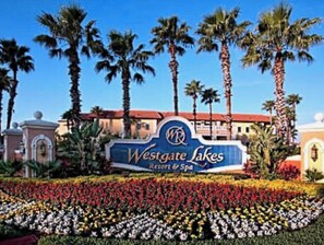 Skilt for Westgate Lakes Resort & Spa omgivet af palmer og en blomsterbed.