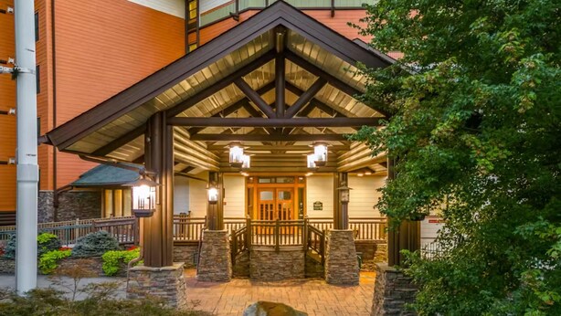 A hotel entrance with a stone facade, wooden porch, and a gated entrance. - Baskins Creek 413 (Gatlinburg)