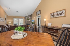 A dining area with a wooden table, chairs, a potted plant, and a fireplace. - Baskins Creek 502 (Gatlinburg)