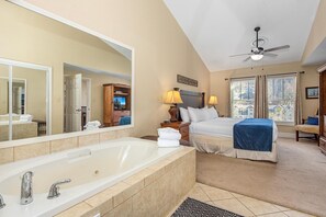 A hotel room with a large bathtub, a bed, a ceiling fan, and a window with curtains. - Baskins Creek 504 (Gatlinburg)