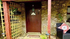 Un edificio de piedra con una puerta de madera, una valla de madera y una silla afuera.