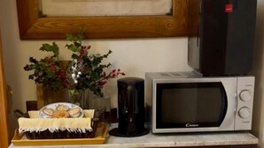 Una cocina con microondas, cafetera y una bandeja de comida.