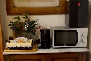 A kitchen with a microwave, a coffee maker, and a tray of food.