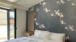 Een slaapkamer met een groot bed, een nachtkastje, een spiegel en uitzicht op het omliggende landschap.
