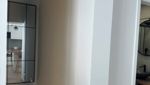 Een modern interieur met een minimalistisch design, met een keukenhoek, een eettafel en stoelen, en een badkamer met een wastafel en spiegel.