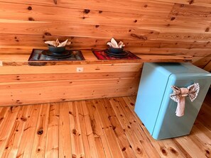L’intérieur d’une cabane en bois, avec deux poêles, un réfrigérateur bleu et un plancher en bois.