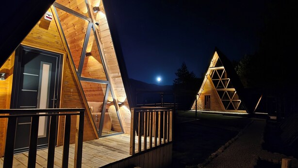 Duas cabanas de madeira triangulares com escadas externas e guarda-corpos de metal.