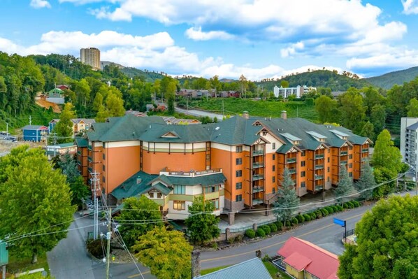 Ein mehrstöckiges Hotel mit geschwungener Fassade, umgeben von Grünflächen und einer hügeligen Landschaft.