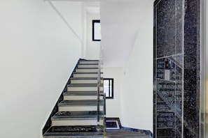 Eine Treppe mit Handlauf, einem kleinen Fenster und einem an der Wand befestigten Schild.