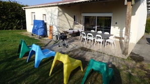 A patio area with a table and chairs, a barbecue grill, and a covered play structure.