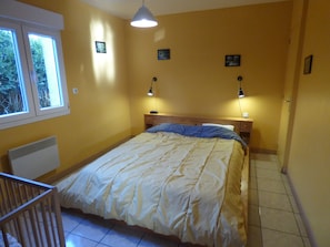 Un dormitorio con cama, lámparas de noche, ventana y radiador.