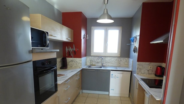 A compact kitchen with a refrigerator, stove, microwave, sink, and cabinets.
