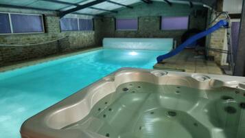 Ein Hallenbad mit einer Whirlpool im Vordergrund und einer Rutsche im Hintergrund.