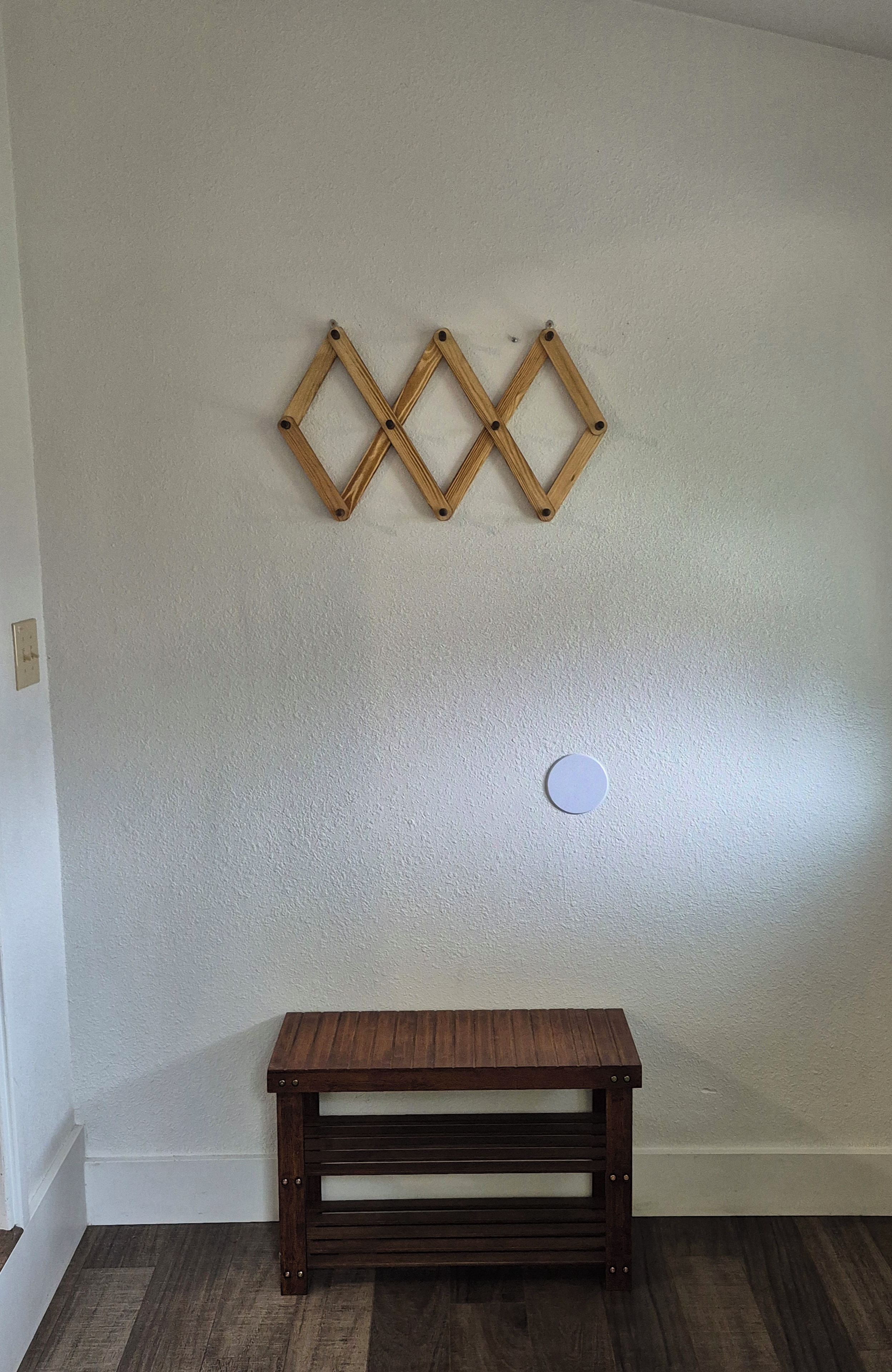 Une pièce avec un banc en bois et trois éléments décoratifs en bois fixés au mur.