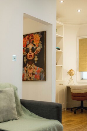 Una habitación con sofá, un cuadro en la pared, un globo terráqueo sobre un pedestal y una ventana con persianas.