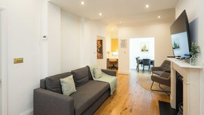 A living room with a sofa, a TV, a fireplace, and a dining area with chairs and a table.