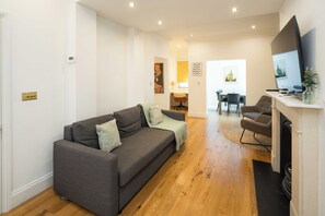 Una sala de estar con un sofá, un televisor, una chimenea y un comedor con sillas y una mesa.