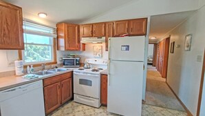 Una cocina con armarios de madera, un refrigerador blanco, una estufa y un lavavajillas.