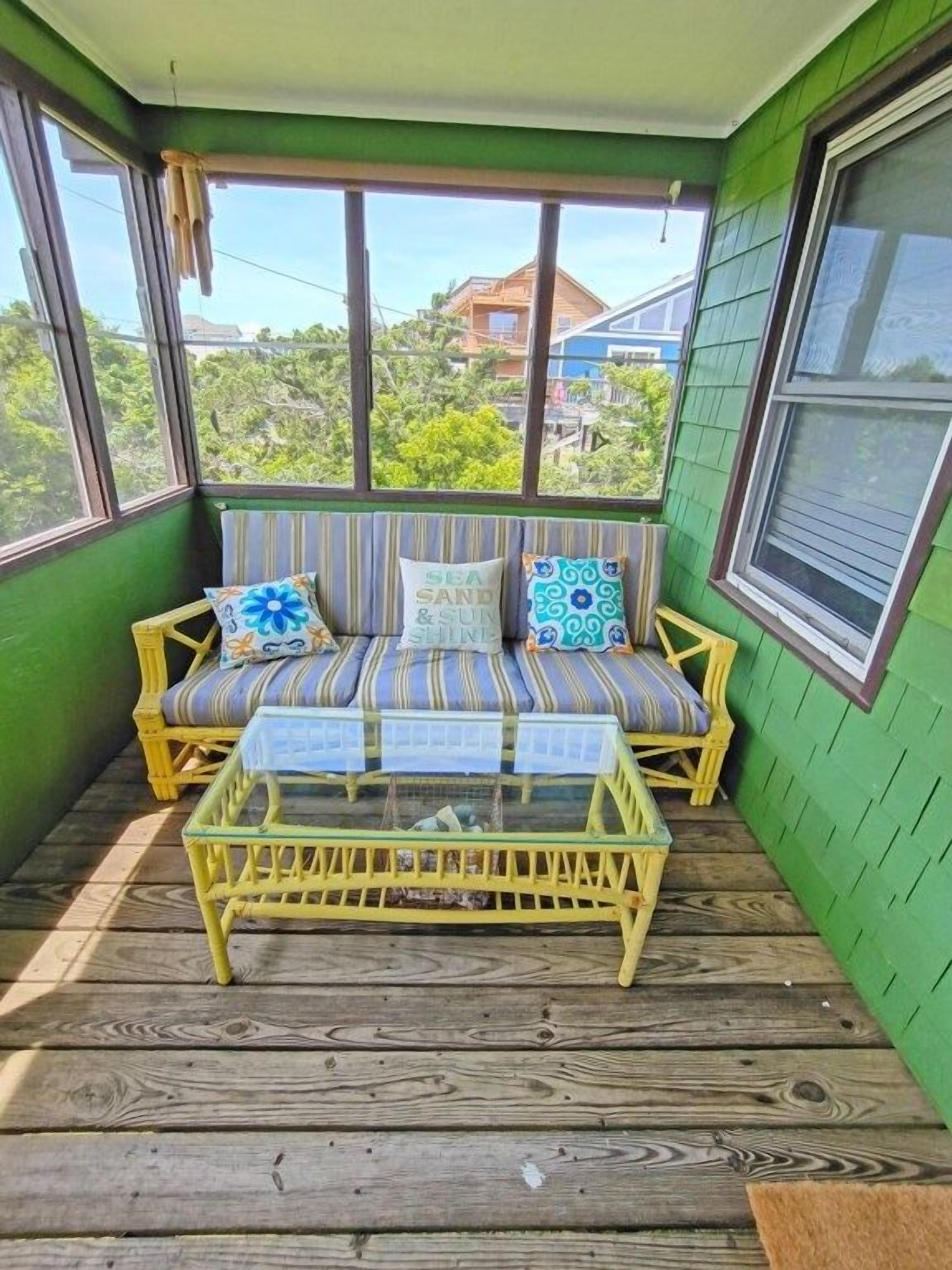 A green room with a yellow sofa and a glass coffee table.