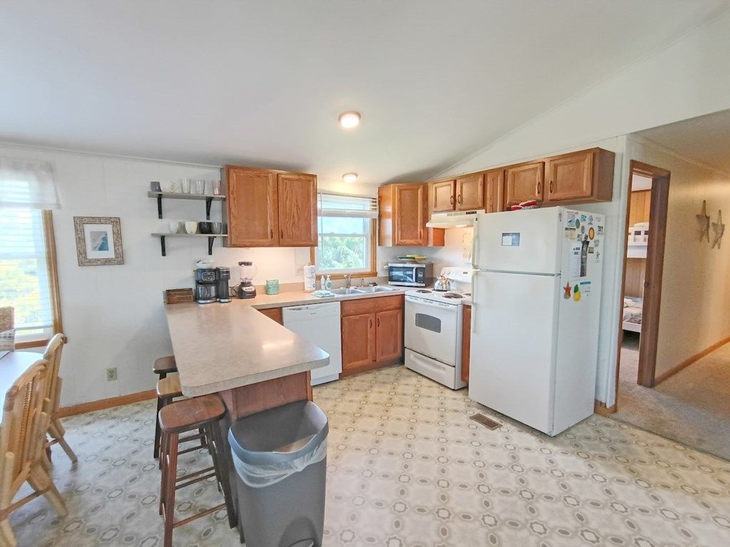 A kitchen with wooden cabinets, a white refrigerator, and a dining area with a table and chairs.