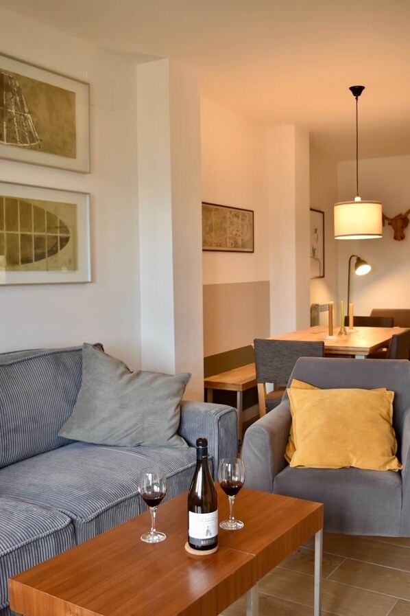 A living room with a sofa, a wooden coffee table, and a dining area with a table and chairs.