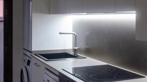 A compact kitchen with a built-in dishwasher, a stovetop, and a sink.