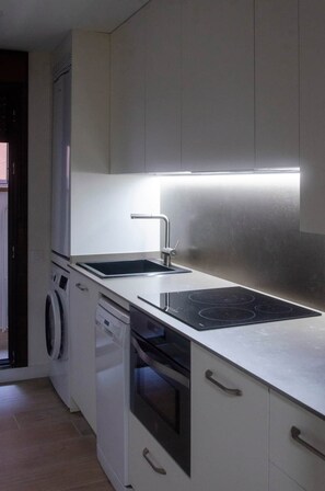 A compact kitchen with a built-in dishwasher, a stovetop, and a sink.