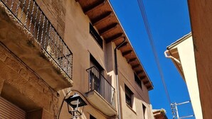 A narrow street with buildings featuring balconies, a street lamp, and a clear blue sky.