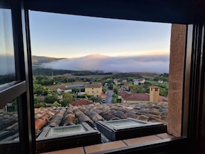 A view from a window overlooking a town with buildings, a road, and a hilly landscape.