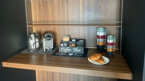En café med kaffemaskine, et skilt der står "Coffee Bar" og et fad med croissanter.