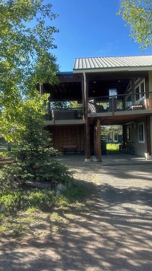 A two-story building with a balcony, a covered porch, and a gravel driveway.
