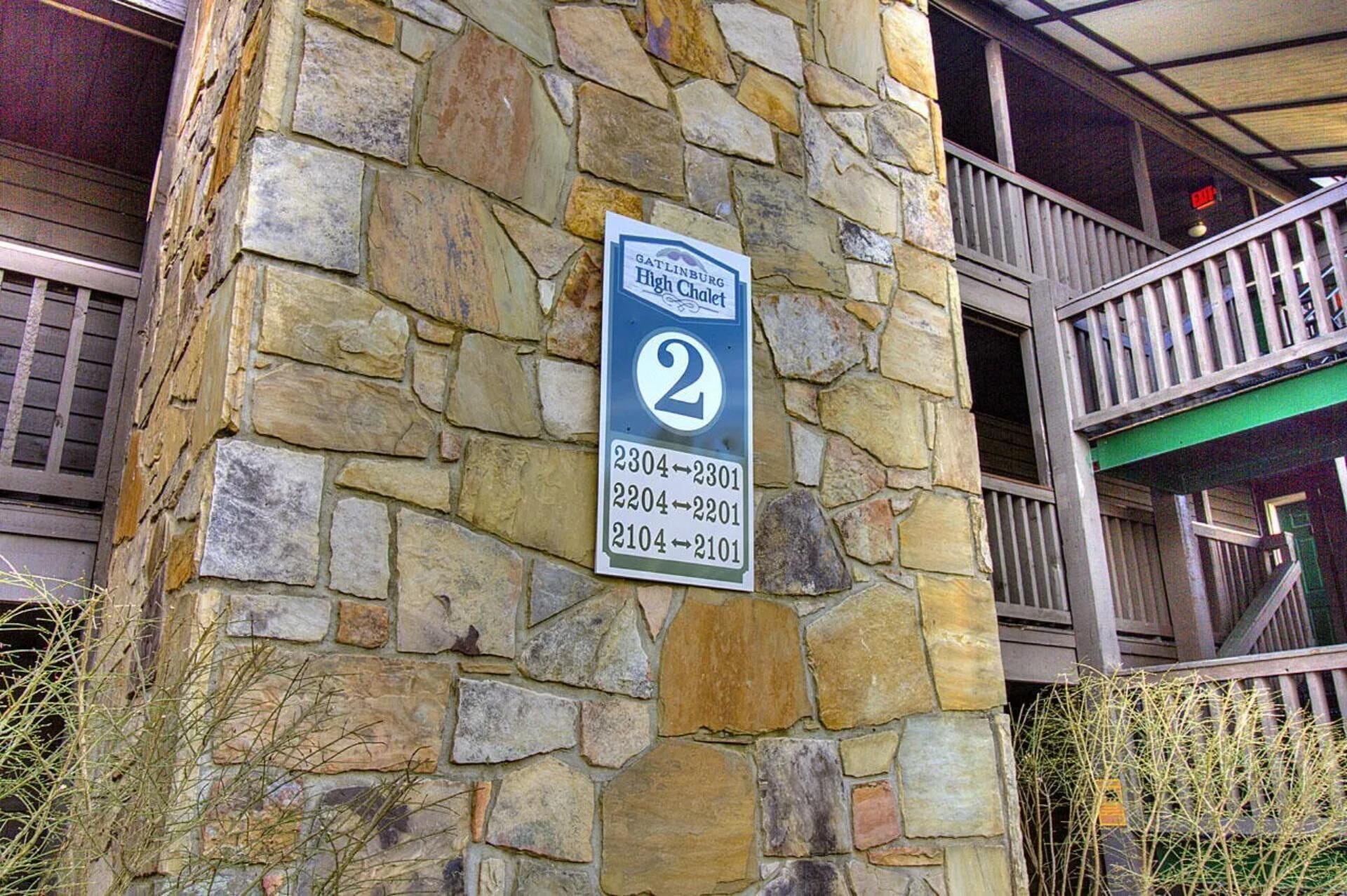 A stone pillar with a sign indicating room numbers and a balcony with a railing.