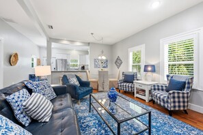 A modern living room with a black leather sofa, blue patterned cushions, a glass coffee table, and a blue patterned rug. - Morning Glory Historic Downtown (St. Augustine)
