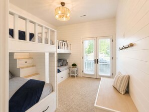A room with a bunk bed, a small table, a bench, and a door with blinds. - Lake Paradise Lakefront Stay (Eldon)