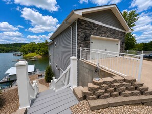 Ein Haus mit Steinverkleidung, einer Garage und einem Bootssteg am See.