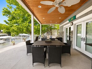 A covered patio with a table and chairs, a ceiling fan, and a view of the water and trees. - Lake Paradise Lakefront Stay (Eldon)