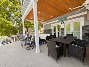 A covered patio with a dining table, chairs, and a stone fireplace. - Lake Paradise Lakefront Stay (Eldon)
