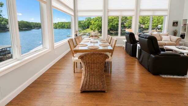 Un salón espacioso con una amplia mesa de comedor, asientos cómodos y ventanas panorámicas con vistas a un lago.