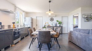 A modern kitchen with a dining table, chairs, and a sofa in a bright, open-plan living area.