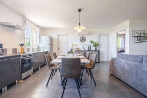 Une cuisine moderne avec une table à manger, des chaises et un canapé, le tout dans un espace de vie lumineux et ouvert.