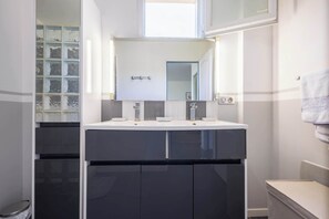 A modern bathroom with a large mirror, two sinks, and a window. - Air-conditioned apartment with outdoor space — Domaine Les Castans, between Agde and Pézenas (Saint-Thibéry)