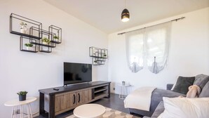 A modern living room with a TV, sofa, and decorative shelves.