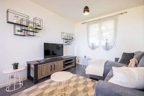 Un salon moderne avec un téléviseur, un canapé et des étagères décoratives.