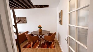 Un coin repas avec une table ronde, quatre chaises, un vase de fleurs et un tapis à motifs.