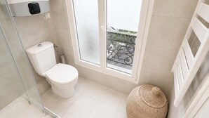 A modern bathroom with a toilet, a glass shower enclosure, and a large window with a view of a balcony. - Charmant Studio Paris 11 - faubourg du temple (Paris)