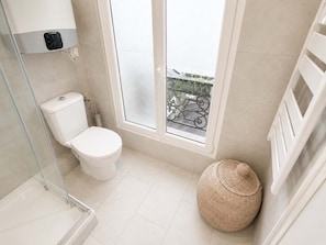 A modern bathroom with a toilet, a glass shower enclosure, and a large window with a view of a balcony. - Charmant Studio Paris 11 - faubourg du temple (Paris)