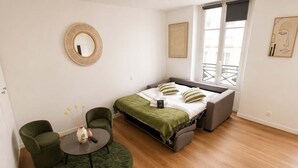 A modern bedroom with a bed, two chairs, a round table, and a window with a view. - Charmant Studio Paris 11 - faubourg du temple (Paris)